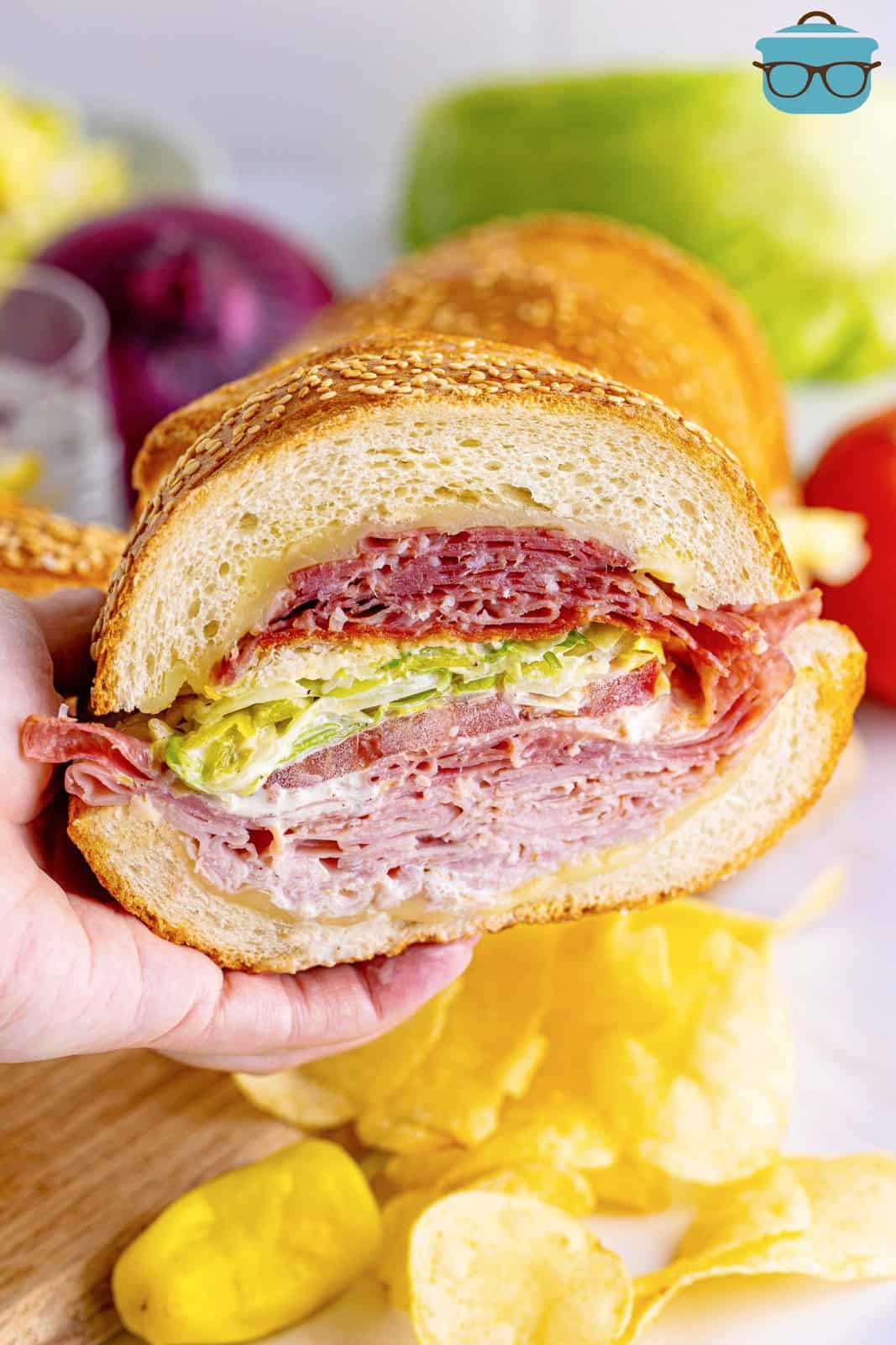 a hand holding up a slice of an Italian grinder sandwich.