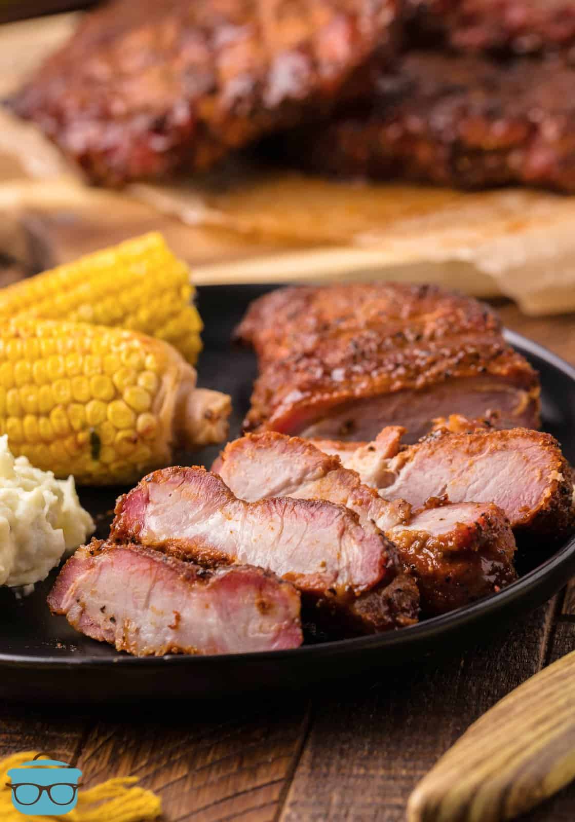 Sliced up Smoked Pork Steaks on plate with corn on the cob.