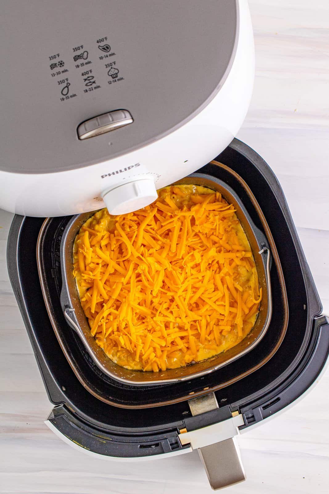 Cheese added to top of Mac and cheese mixture in air fryer.