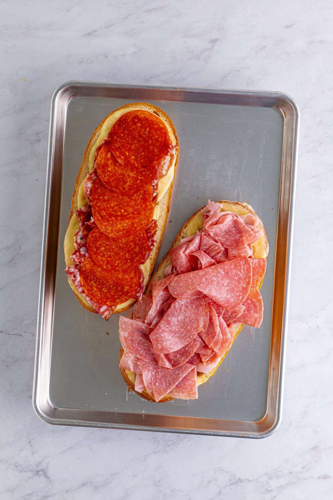 slices of pepperoni added to one side of the sub rolls and sliced salami added to the other side of the sub rolls.