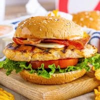 Close up square image of Chick-fil-A Grilled Chicken Club Sandwich on wooden board.