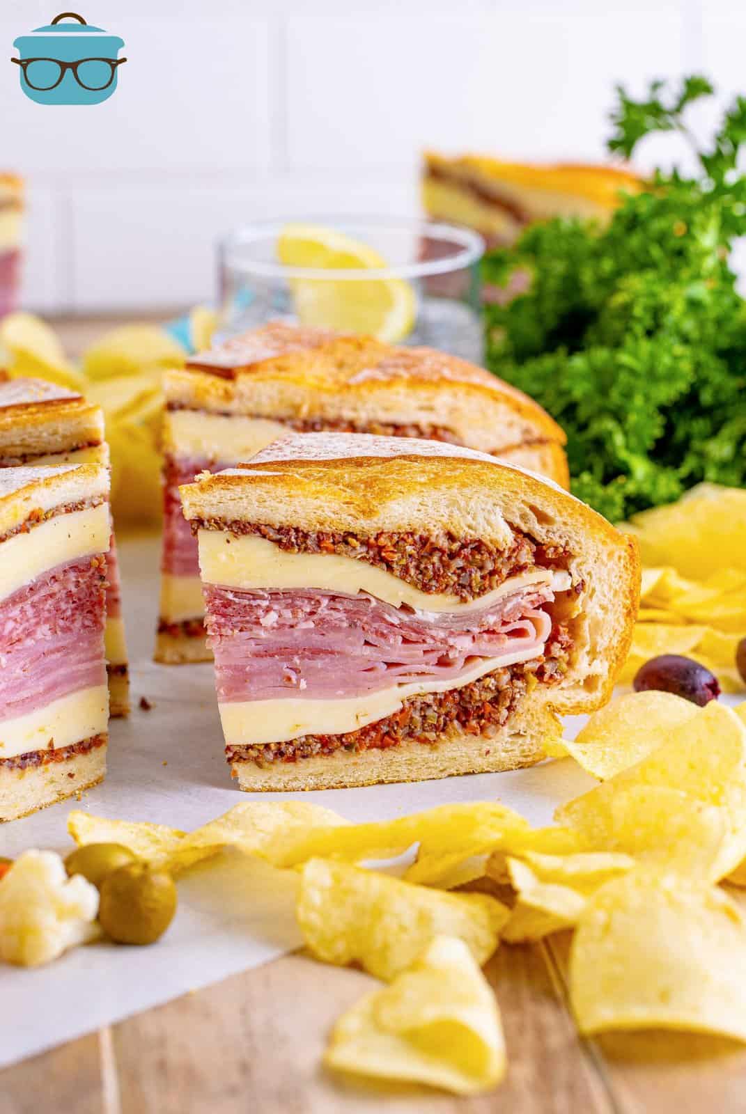 Slice of the Muffaletta Sandwich with chips in front showing layers.