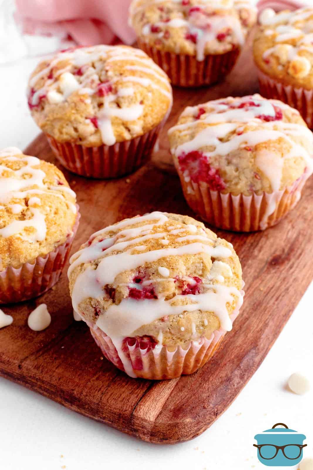 Raspberry White Chocolate Muffins on wooden board with glaze.