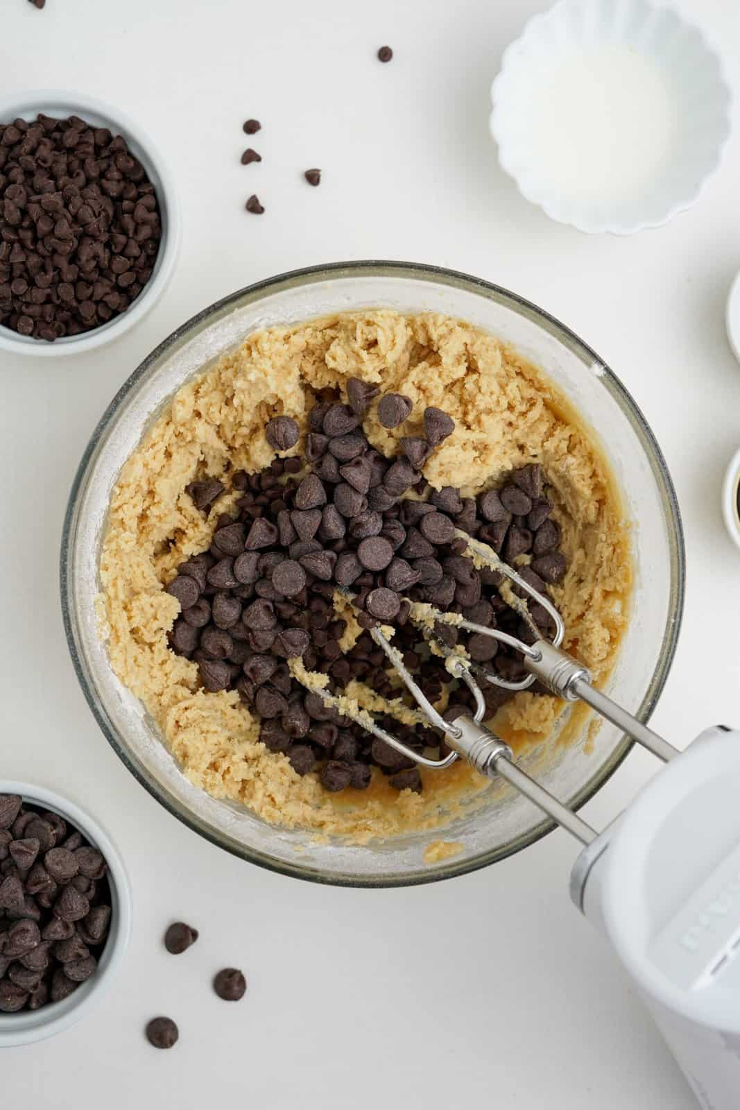 Chocolate chips added to dough in bowl.
