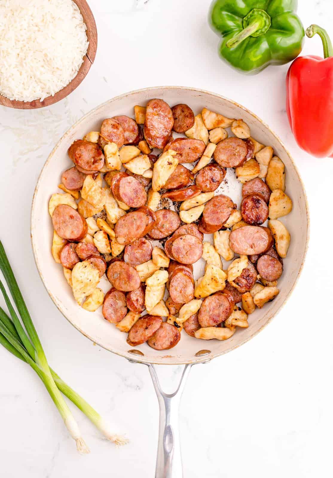 Chicken and sausage browned in pan.