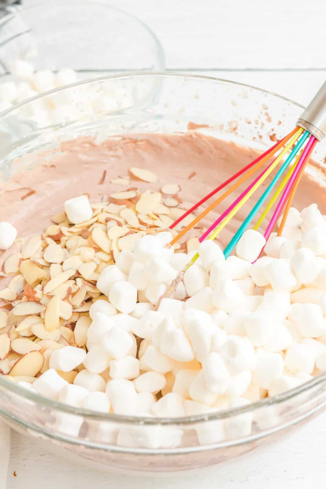 Mini marshmallow e mandorle aggiunti alla miscela di gelato in una ciotola.