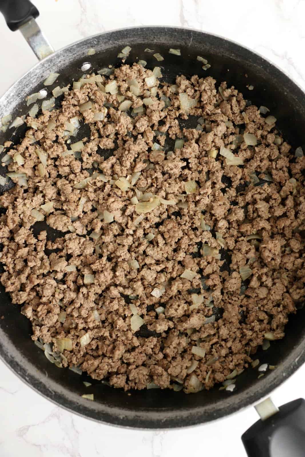 Cooked ground beef and onion in pan.