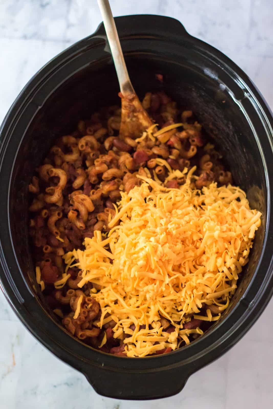 Half the shredded cheese added to slow cooker.