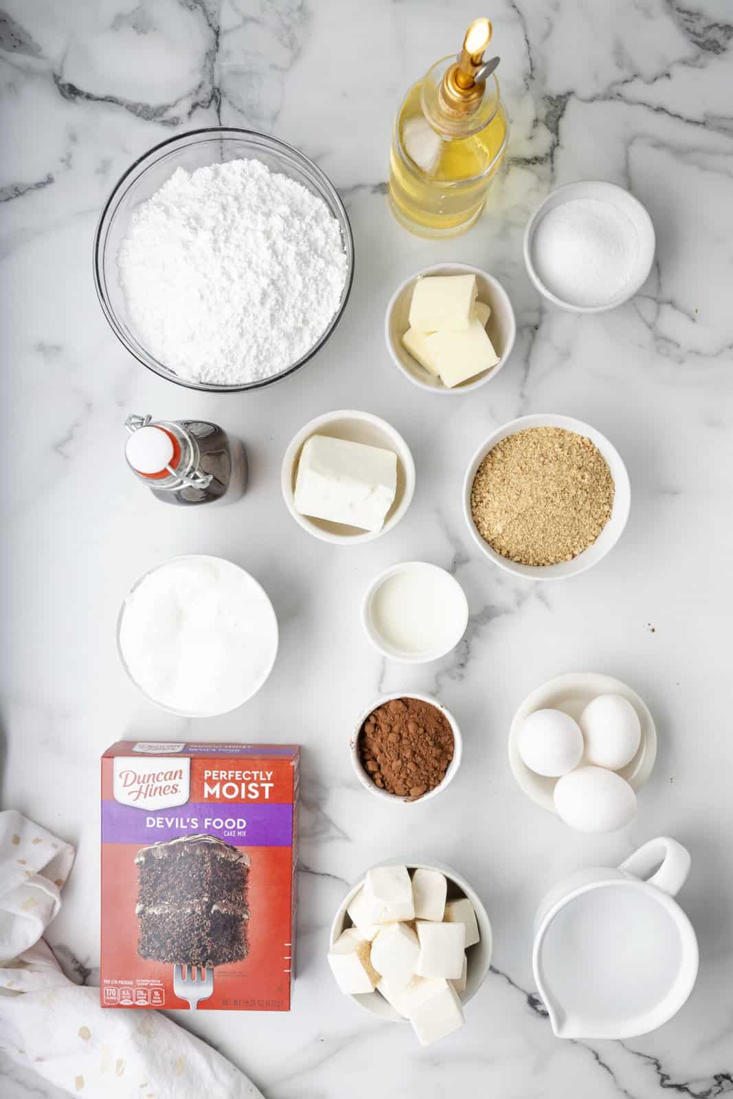 Ingredients needed: graham cracker crumbs, granulated sugar, butter, chocolate cake mix, ingredients to make cake mix, salted butter, shortening, marshmallow fluff, powdered sugar, cocoa powder, milk, vanilla extract and marshmallows.