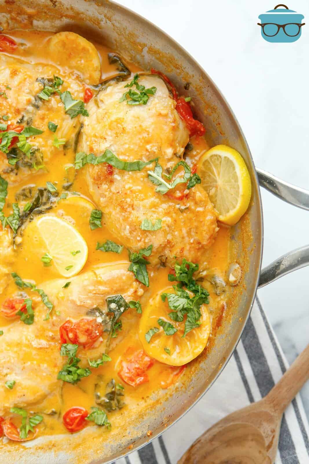 Overhead of Creamy Lemon Chicken Skillet in pan showing lemons and garnishes.