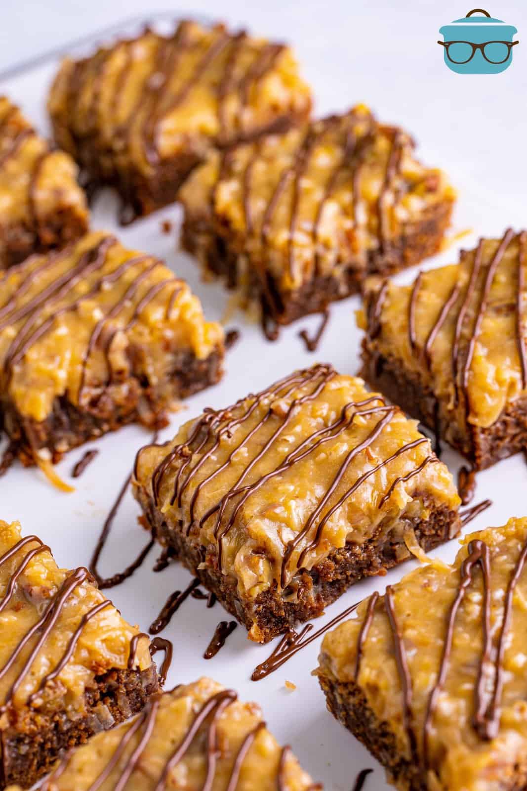 Sliced up German Chocolate Brownies drizzled with chocolate on parchment.