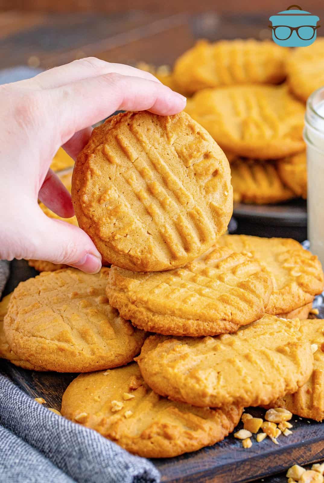 Stacked Lunch Lady Peanut Butter Cookies with hand holding one up slightly.