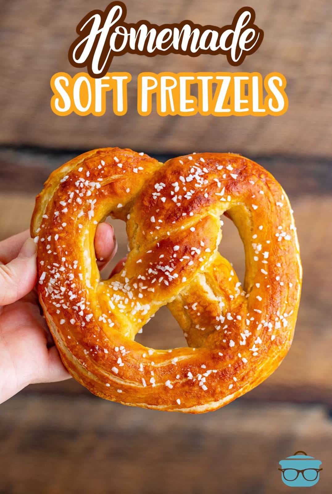 Pinterest image of hand holding up one of the Homemade Soft Pretzels.