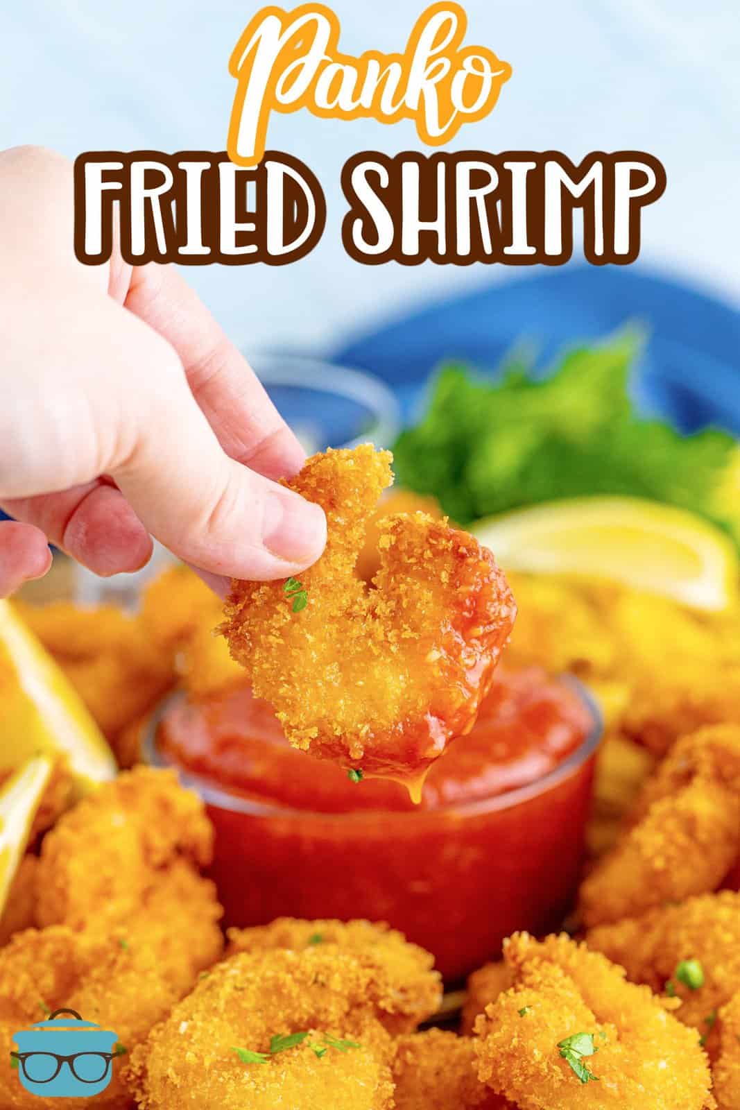 Hand dipping one Fried Panko Shrimp into cocktail sauce.