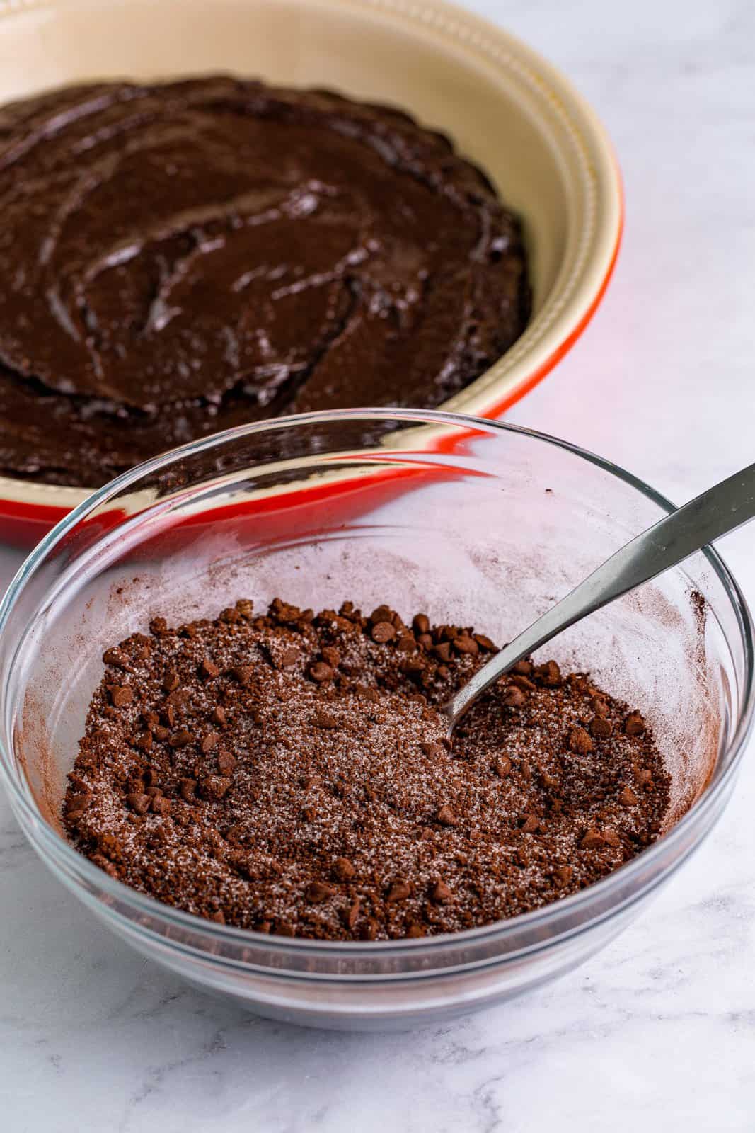 Sugar, brown sugar, cocoa powder, and chocolate chips stirred together in bowl.