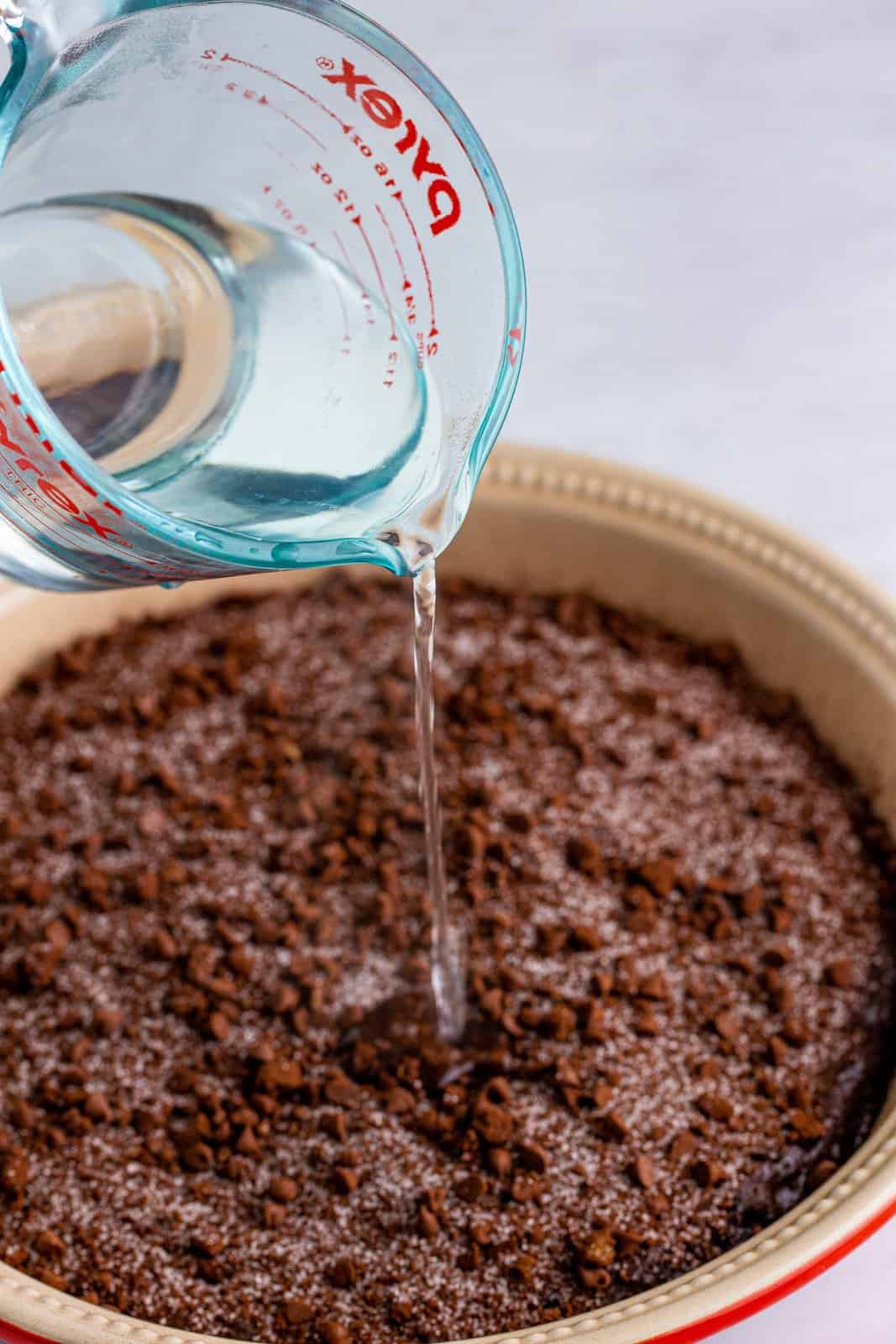 Water being poured over cake in baking dish.