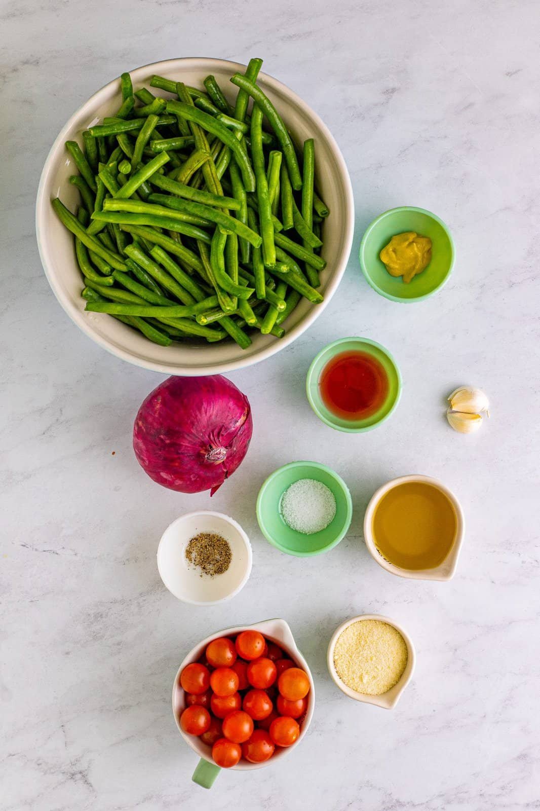 Ingredients needed: fresh green beans, olive oil, red wine vinegar, garlic, dijon mustard, kosher salt, pepper, red onion, cherry tomatoes and parmesan cheese.