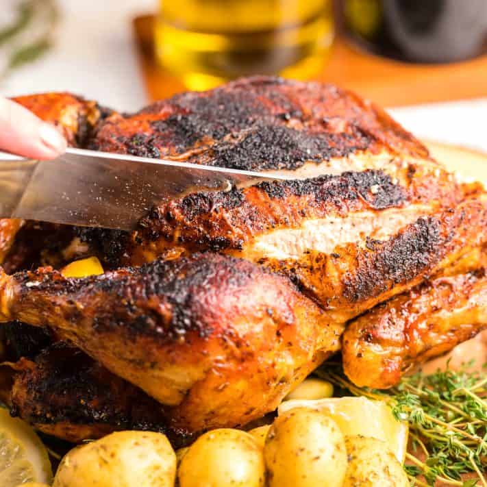 Square image of knife cutting into Air Fryer Whole Roasted Chicken.