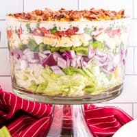 Square image of finished layered Seven Layer Salad in trifle dish.