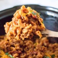 Close up image of Slow Cooker Chili Mac being lifted up with wooden spoon.