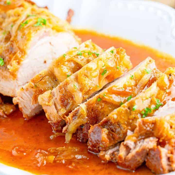 Square image close up of sliced Crock Pot Pork Loin on plate with gravy.