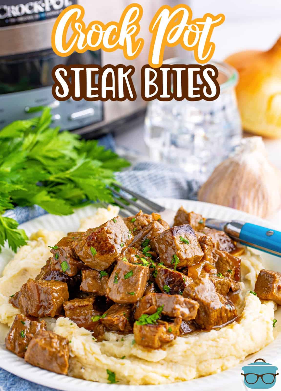 Pinterest image of Slow Cooker Garlic Butter Steak Bites with mashed potatoes and slow cooker and water in background.