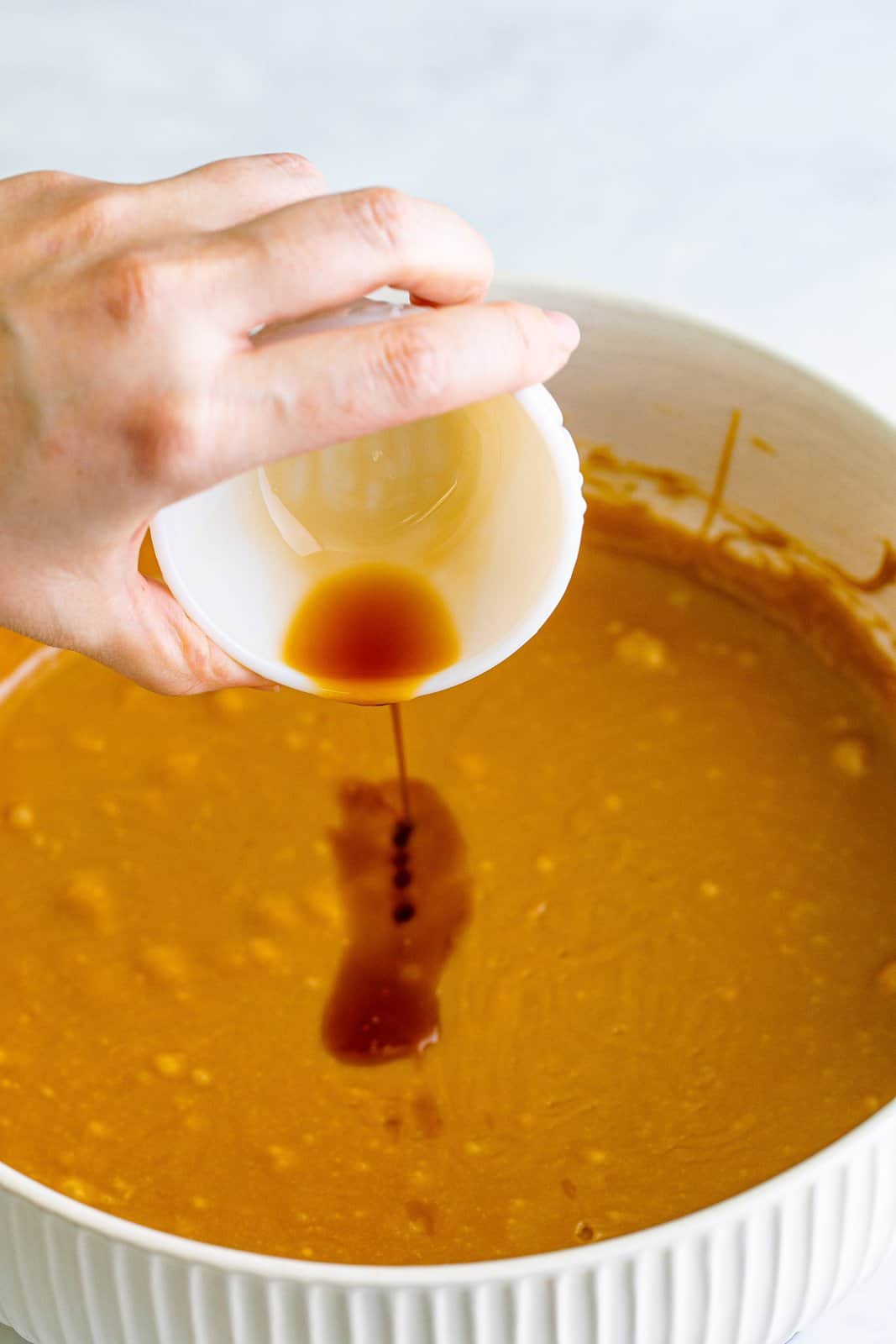 Vanilla being added to caramel mixture in bowl.