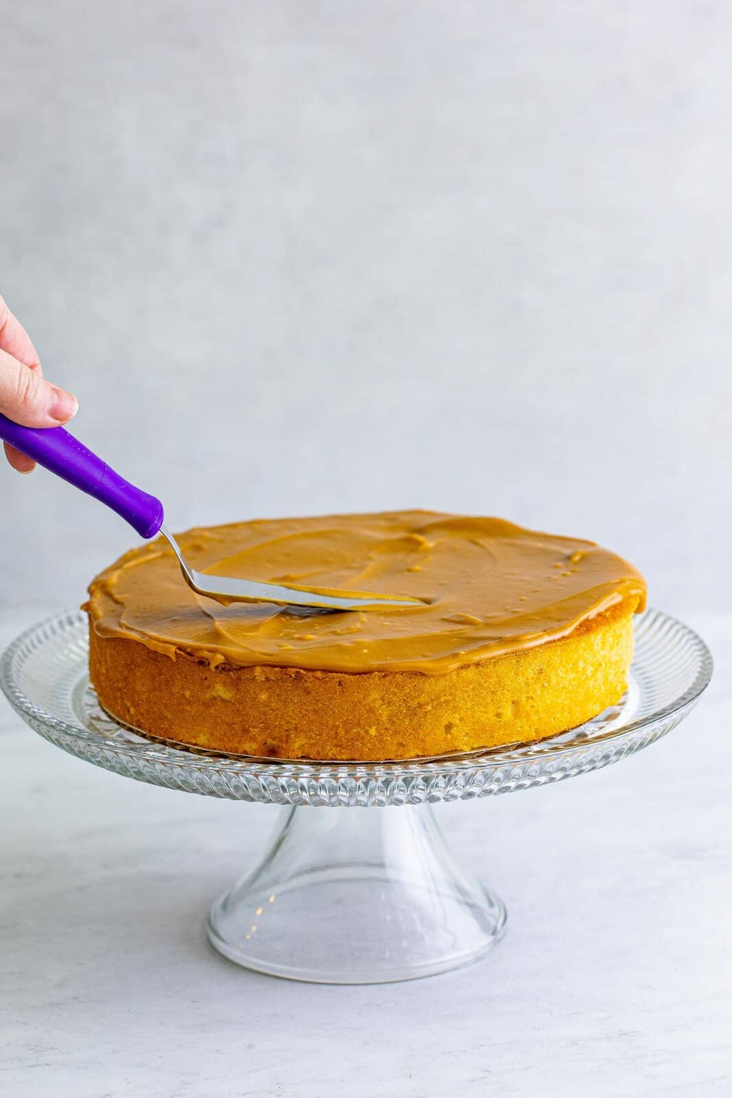 One cake layer being spread with caramel frosting.