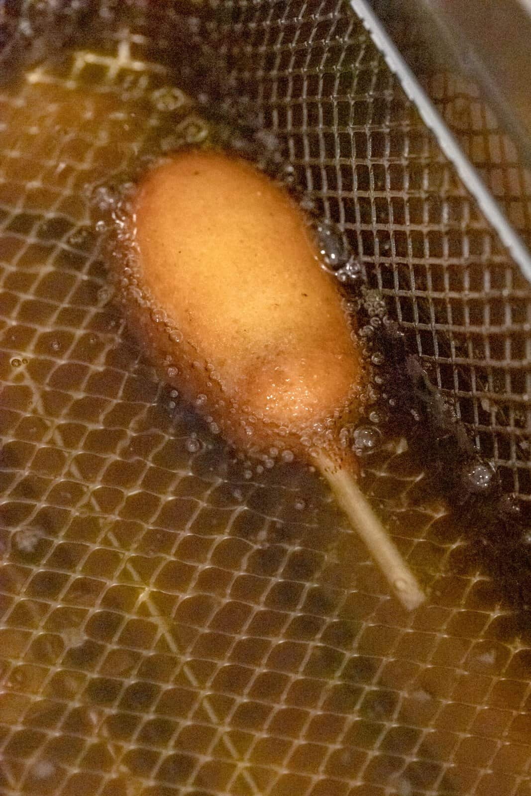 Corn dog placed in oil frying.