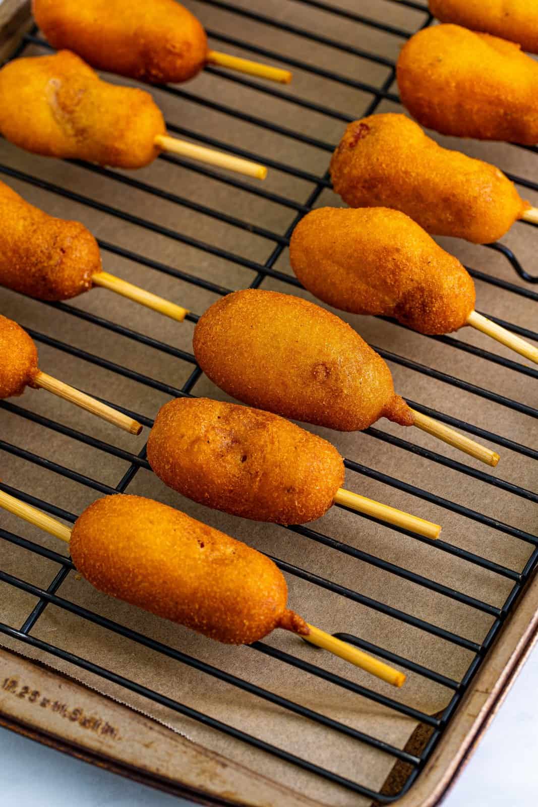 Corn Dogs placed on wire rack over sheet pan.