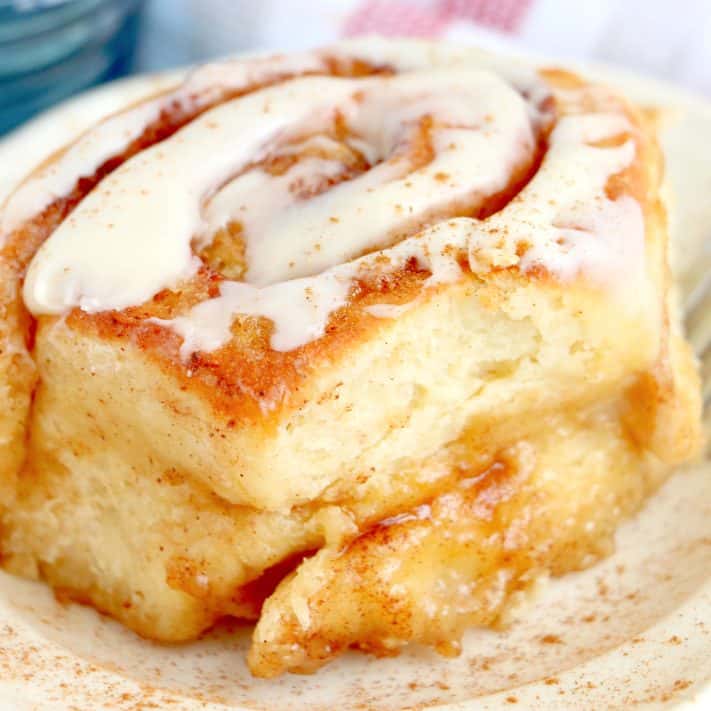 Close up square image of one of the Air Fryer Cinnamon Rolls on plate with glaze.