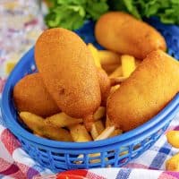 Close up square image of Mini Homemade Corn Dogs in basket with French fries.