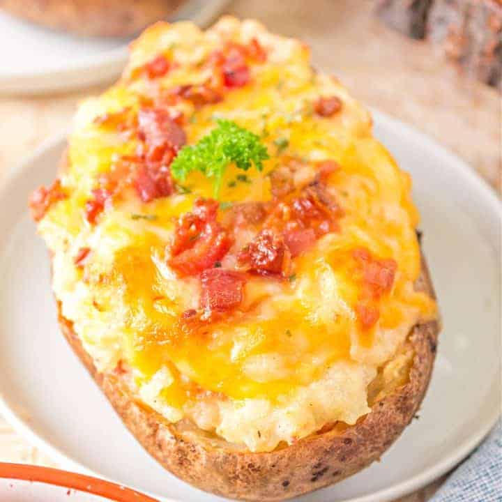 Close up square image of one of the Grilled Twice Baked Potatoes on white plate showing bacon.