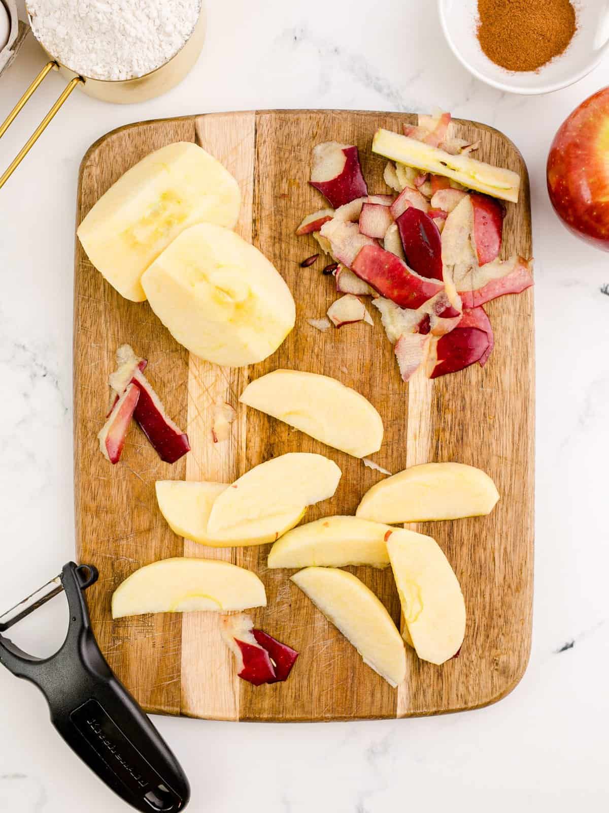 Apples peeled, cored and sliced on cutting board.