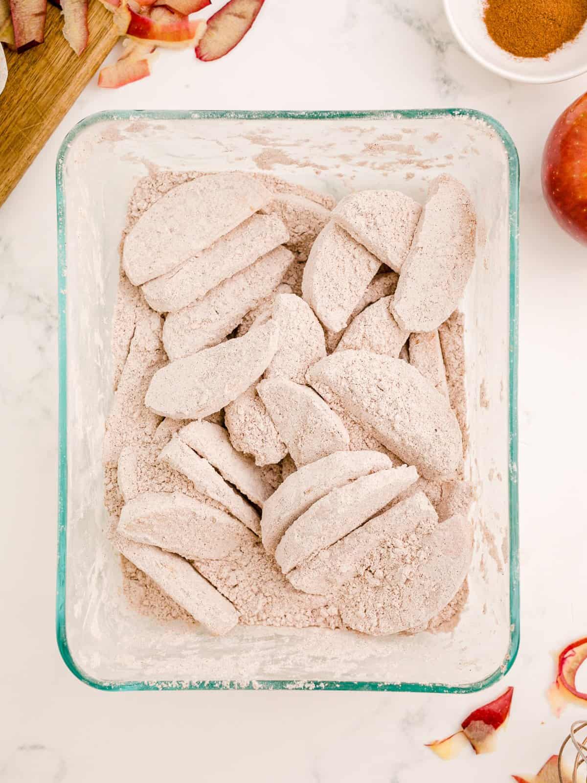 Apples coated in flour mixture in container.