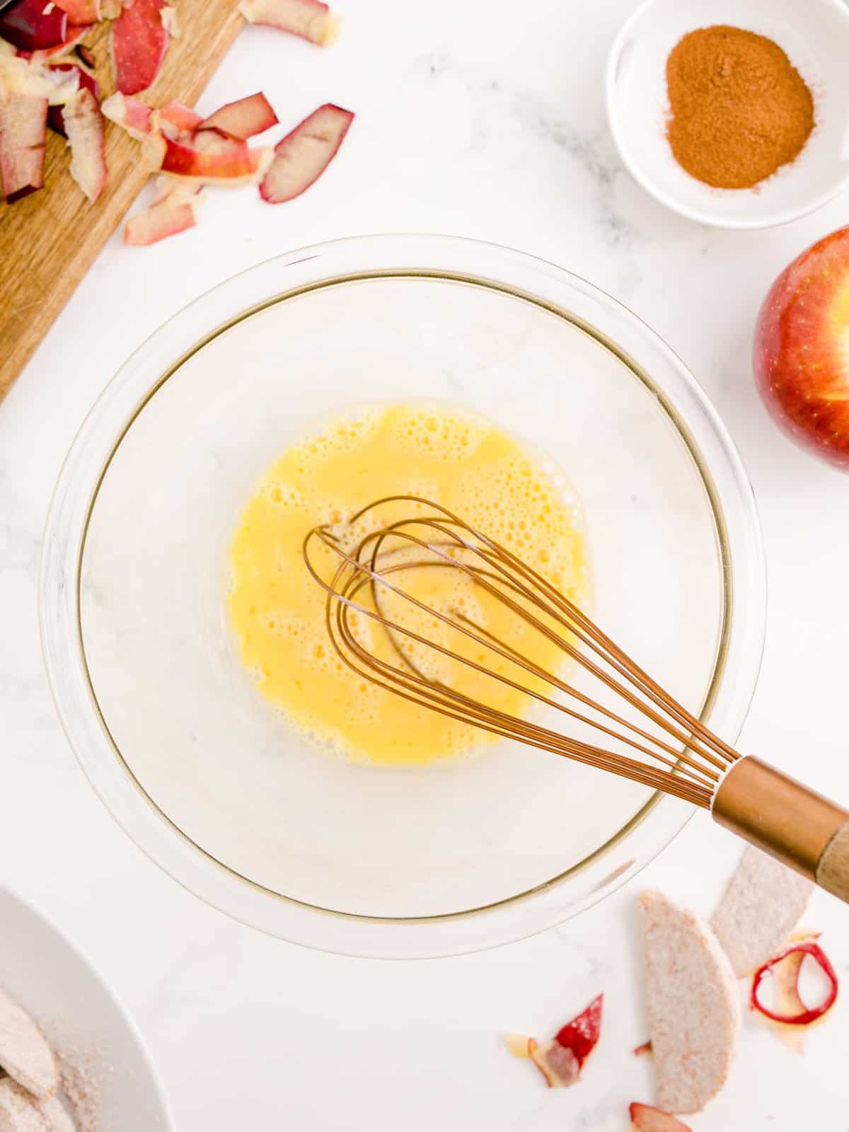 Eggs and vanilla whisked together in bowl.