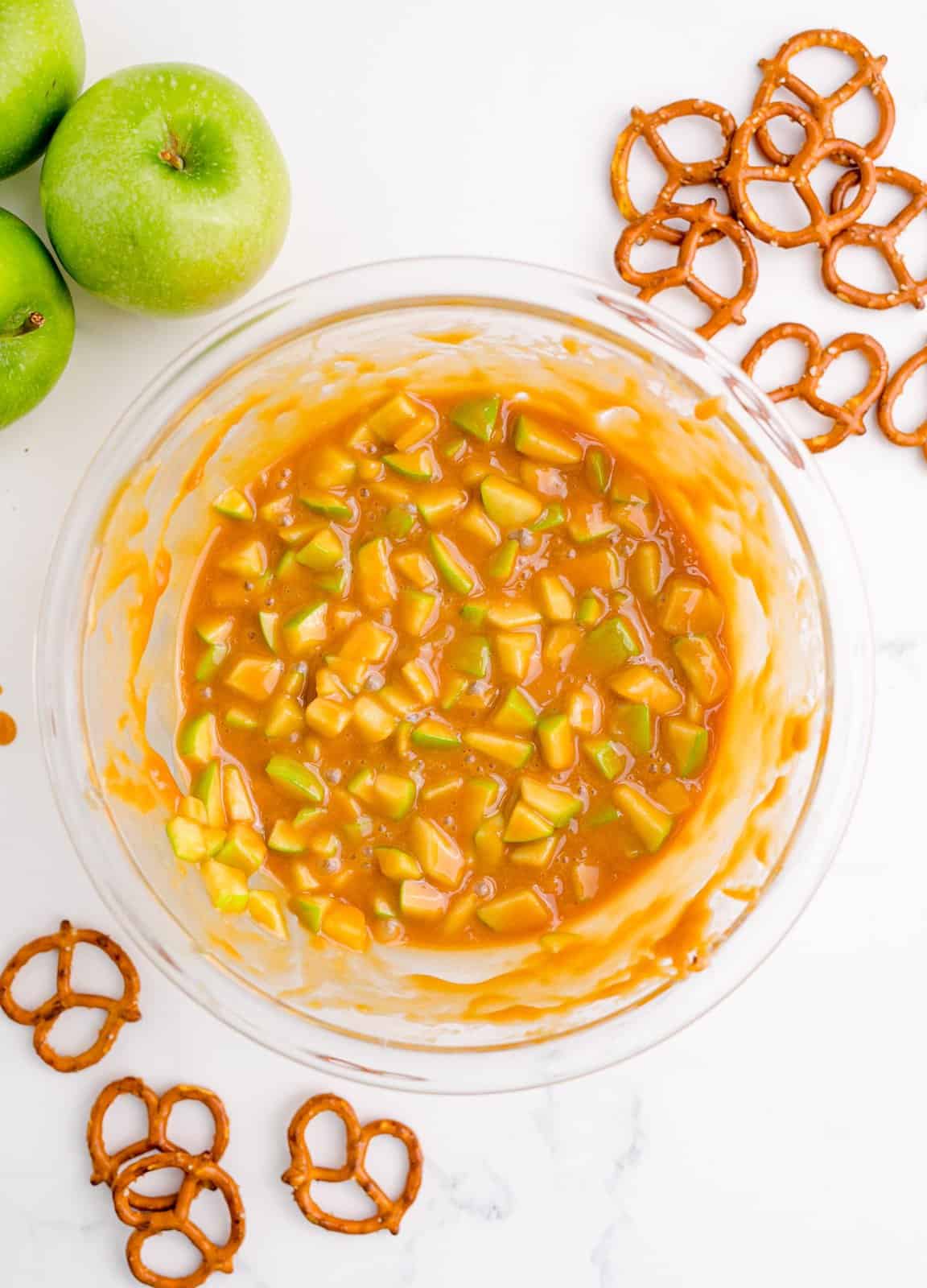 Caramel and apples mixed together in bowl.