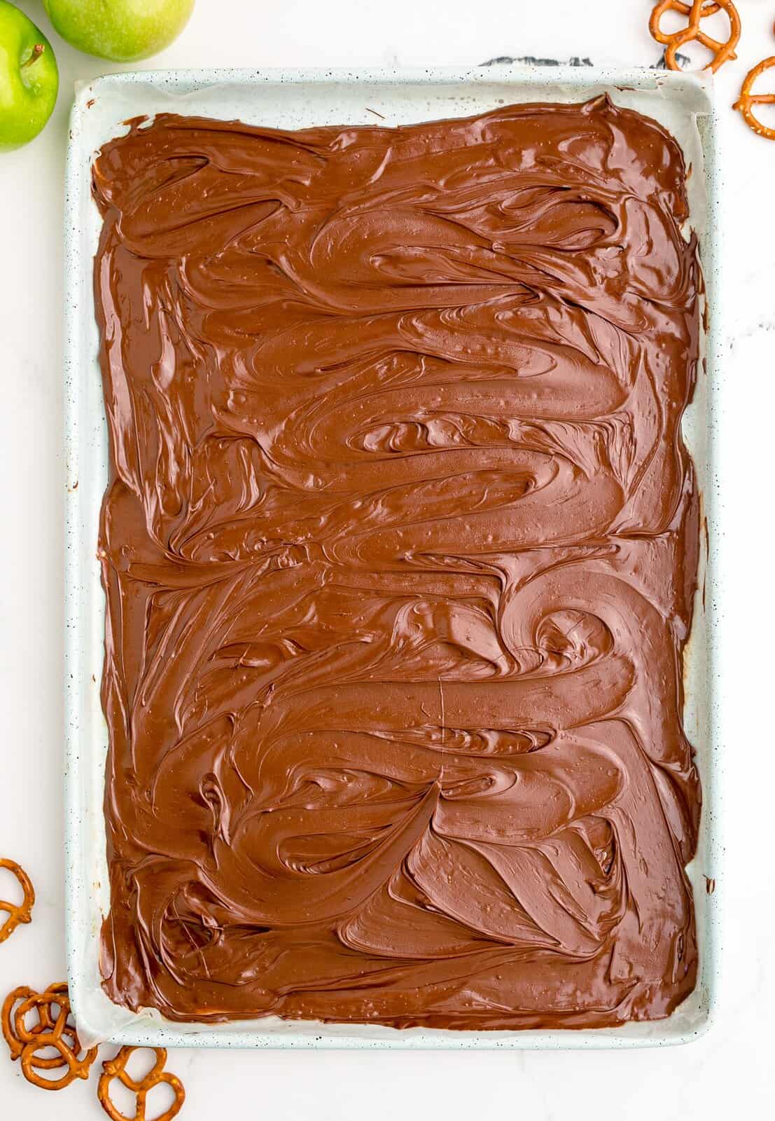 Melted chocolate spread out over parchment lined baking sheet.