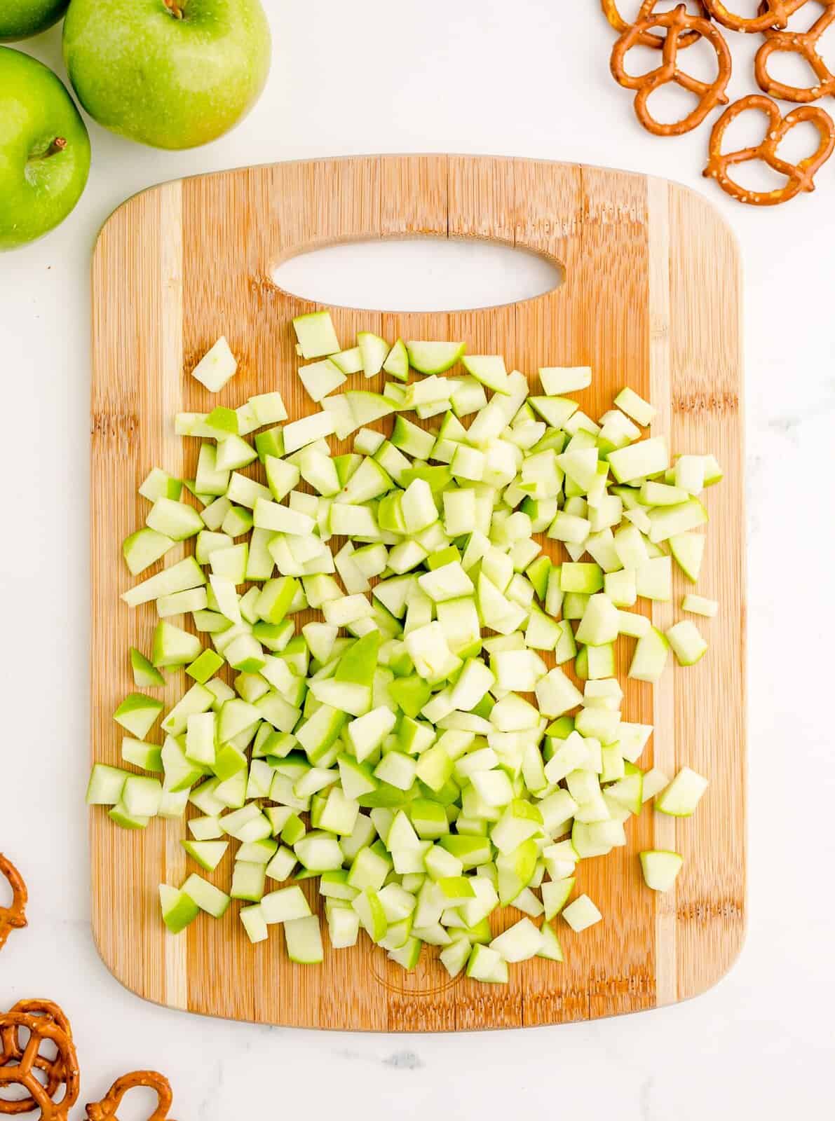 Apples diced up on wooden cutting board.