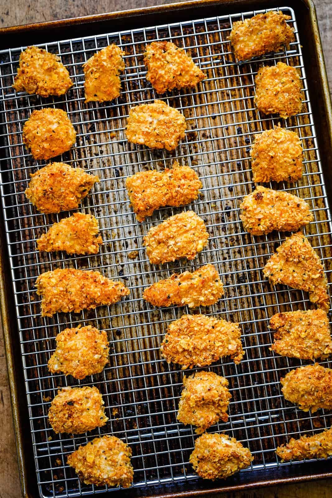Finished chicken nuggets on wire rack over baking pan.