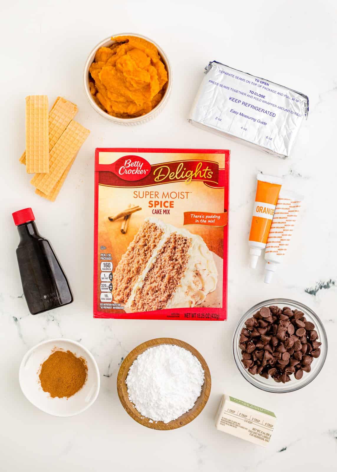Ingredients needed: spice cake mix, pumpkin puree, cinnamon, cream cheese, Orange and Green food coloring, salted butter, vanilla extract, powdered sugar, wafer cookies and semi-sweet chocolate chips.