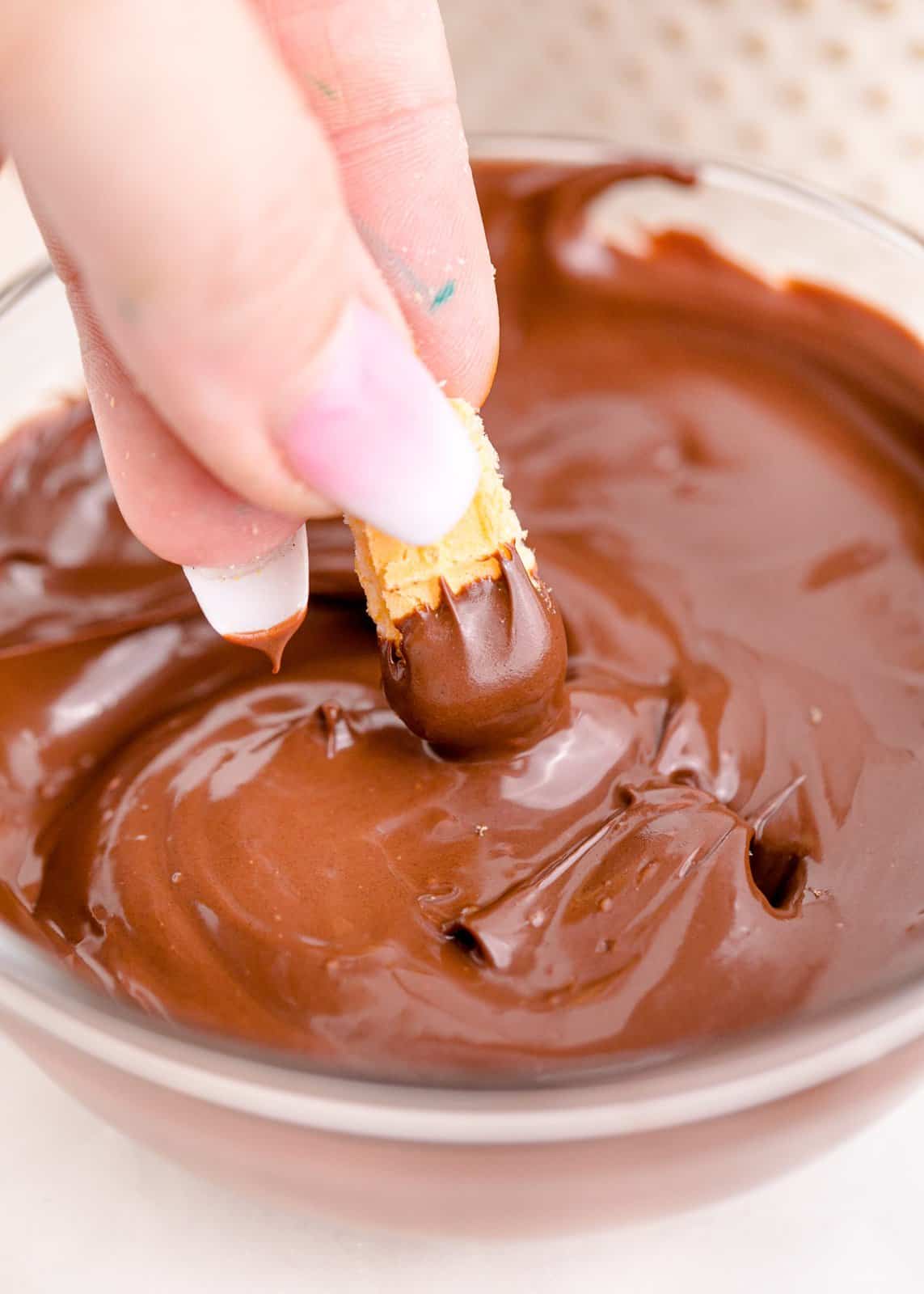 Melted chocolate with wafer cookie being dipped into it.