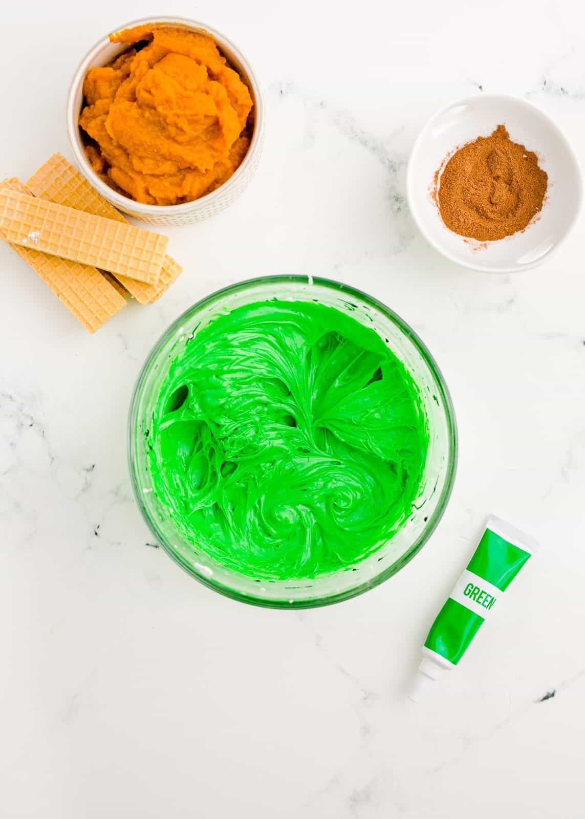 Cream cheese frosting in bowl with green food coloring.