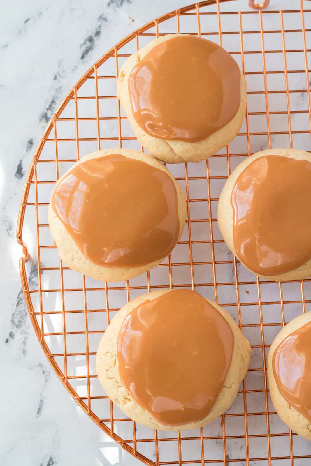 Caramel spread on top of cookies on wire rack.