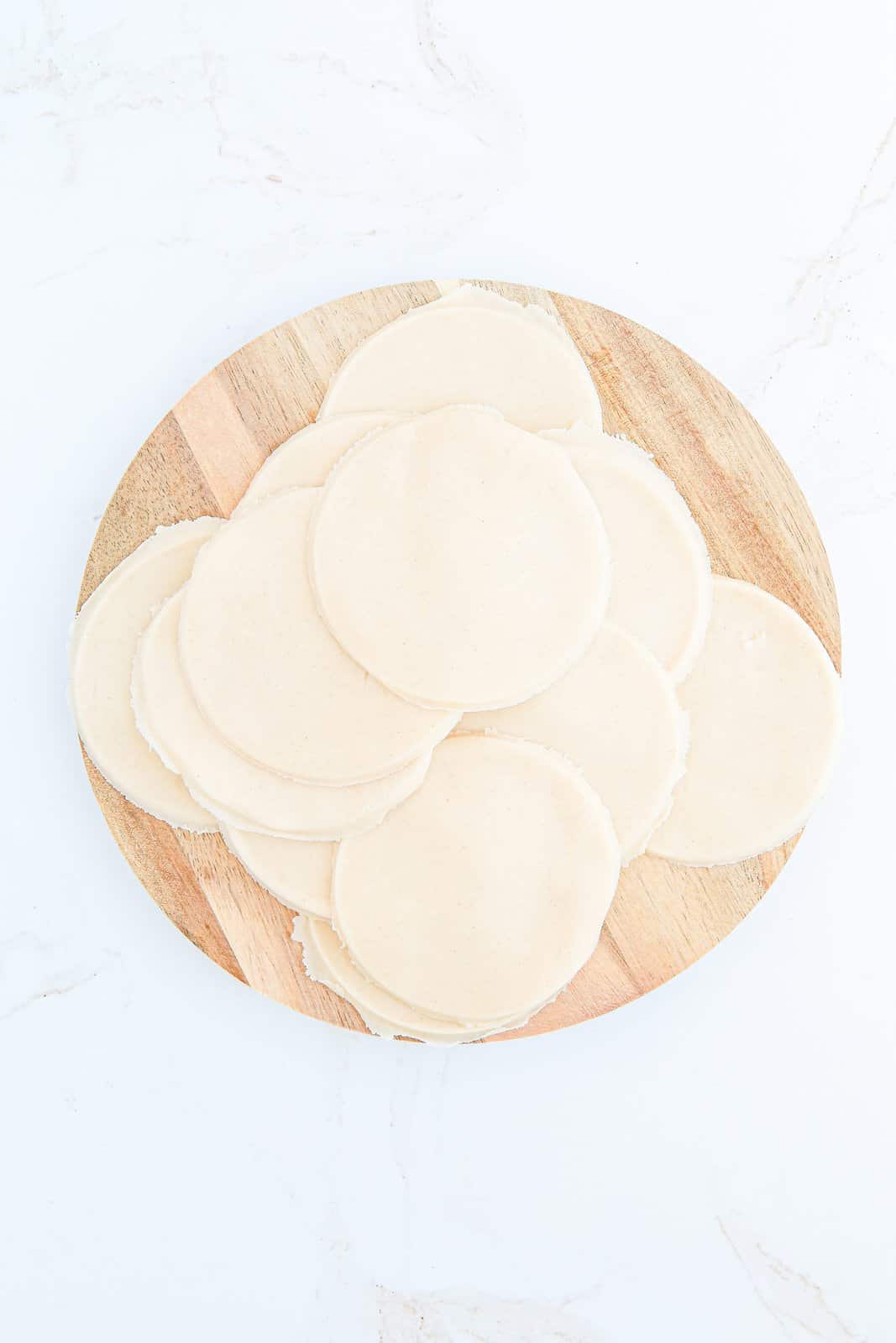 Pie crust cut into circles on wooden board.