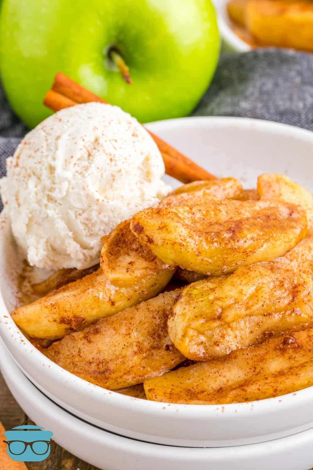 Air Fryer Fried Apples in white stacked bowls with scoop of ice cream and cinnamon stick.
