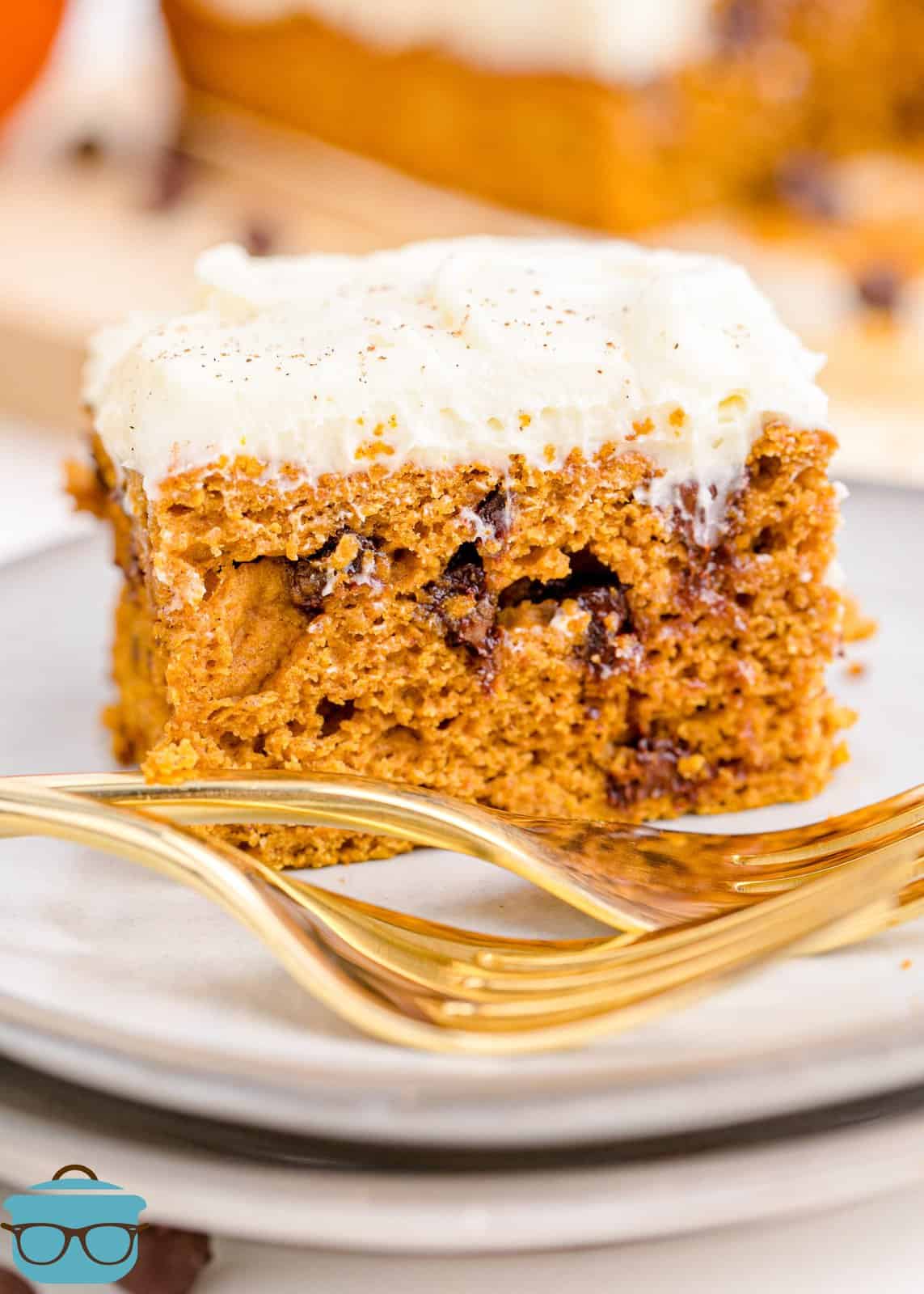 Slice of Pumpkin Chocolate Chip Cake on white plat with gold forks.