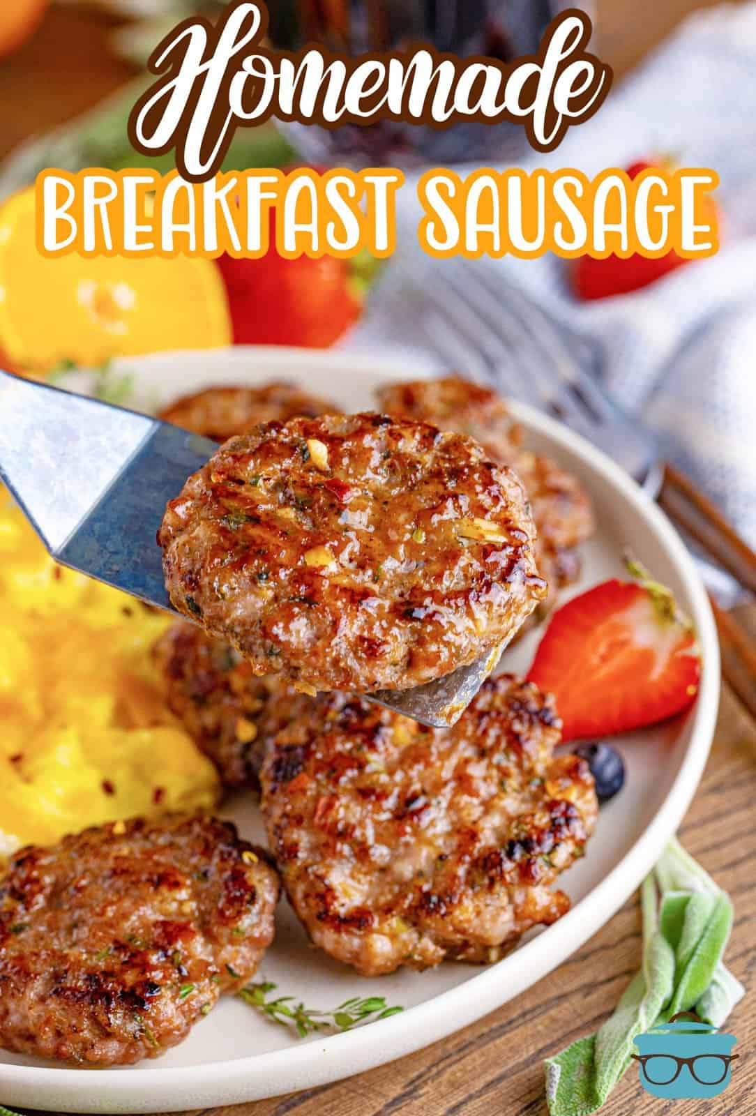 Pinterest image of Homemade Breakfast Sausage being held up with metal spatula over plate with eggs and fruit.