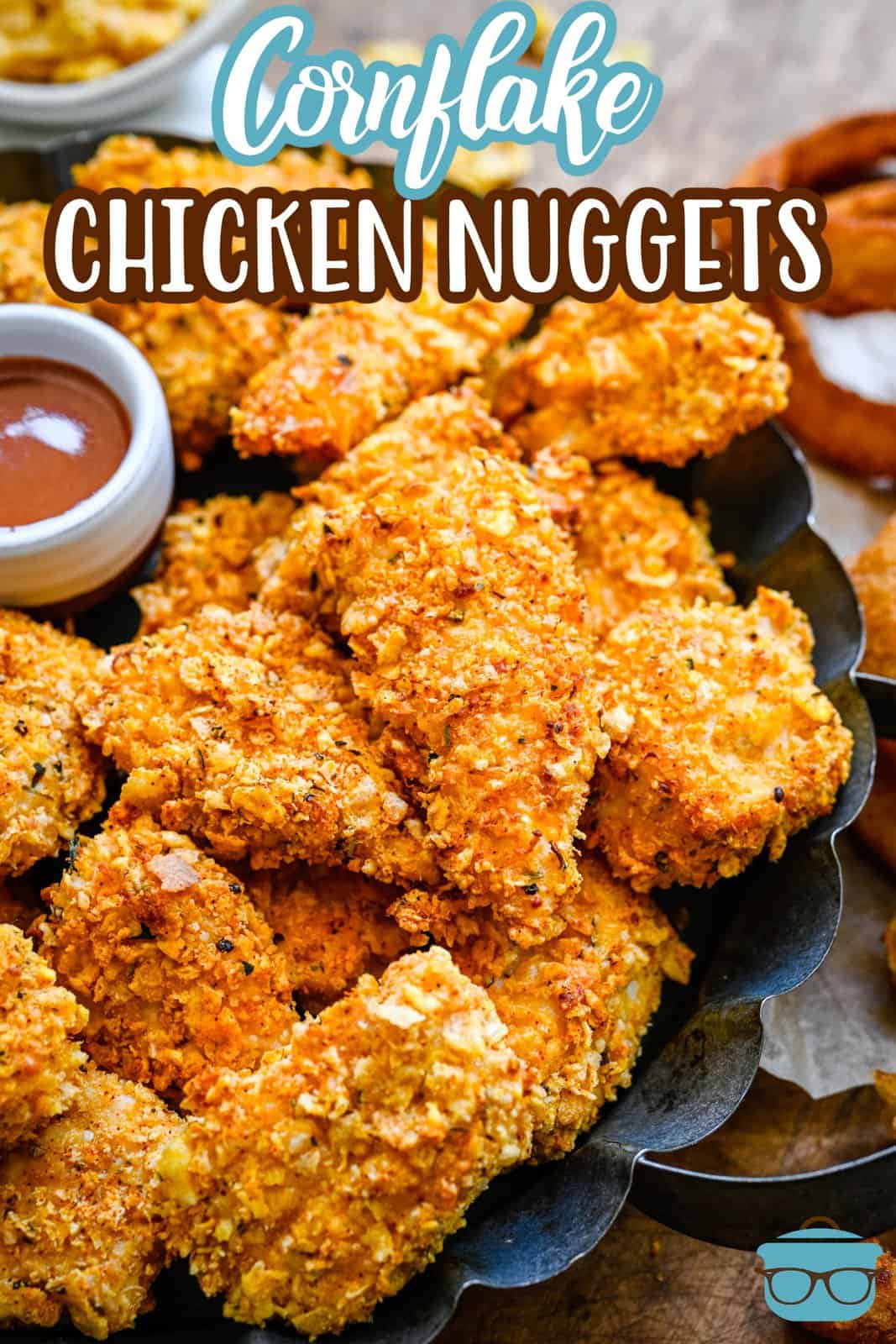 Pinterest image of Cornflake Chicken Nuggets on black platter stacked with dipping sauce.