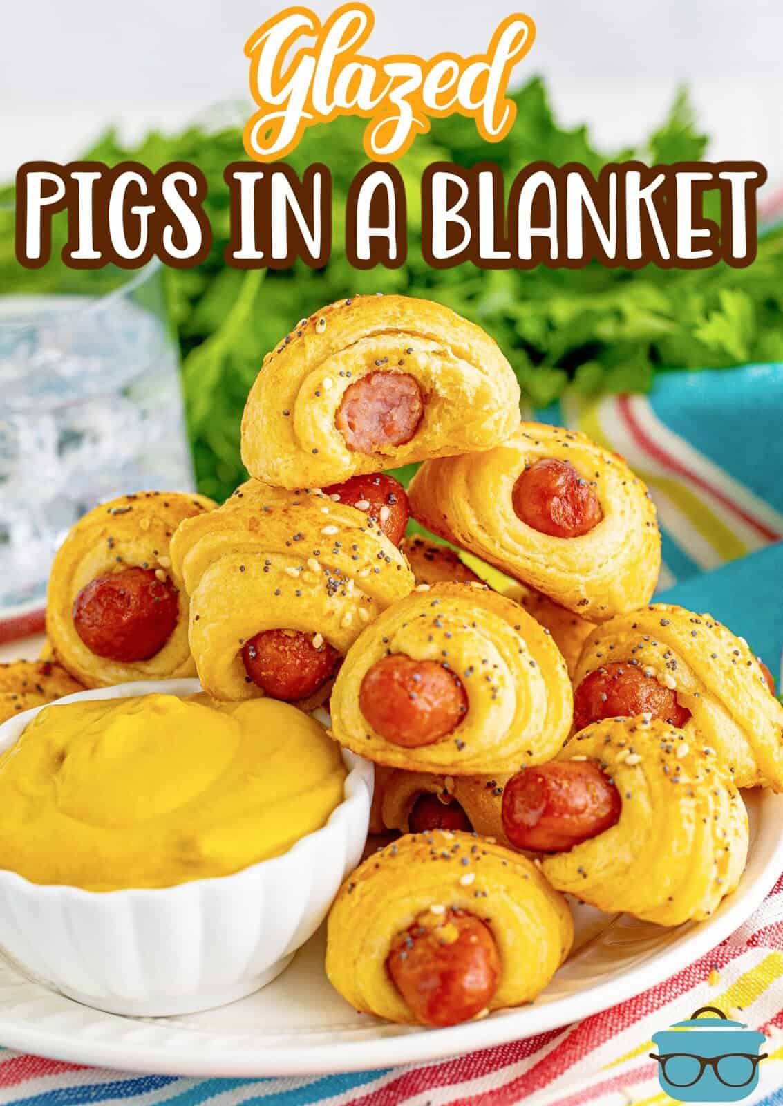 Pinterest image of stacked Glazed Pigs in a Blanket with bite taken out of top one on plate with dipping sauce.